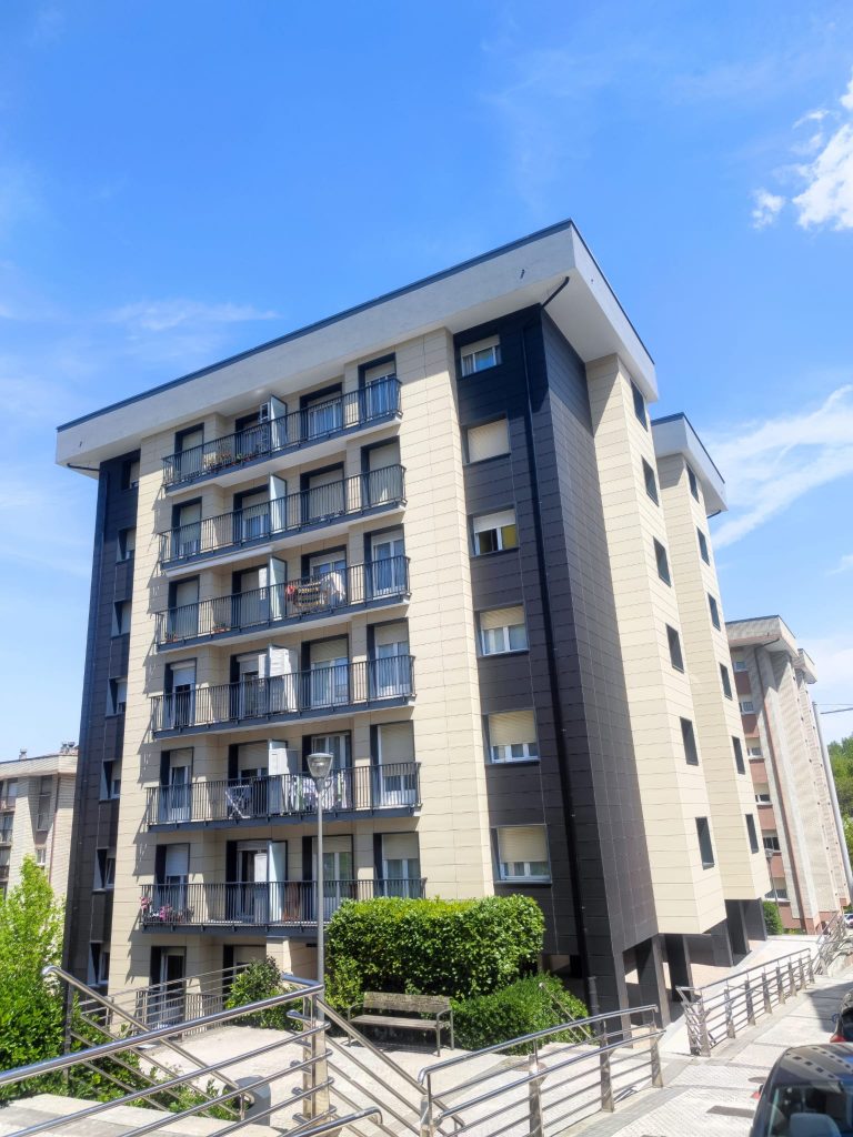 Edificio residencial de seis plantas rehabilitado en Gipuzkoa, con fachada renovada y barandillas metálicas modernas.