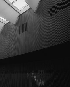 Interior rehabilitado con diseño contemporáneo en Gipuzkoa, con paredes revestidas de listones verticales y entrada de luz cenital.